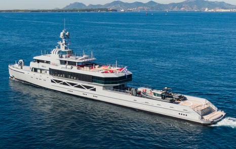 A port-side, top-down view of superyacht BOLD making way at sea with landfall in the background