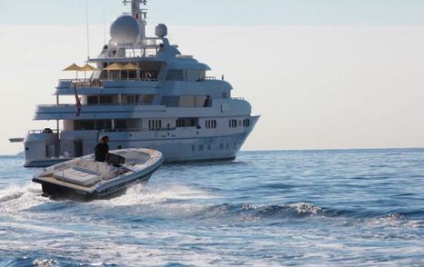 Chase boat moving at speed on sea with larger superyacht in background