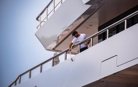 mage shows yacht crew on side of yacht preparing for display at MYS 2024