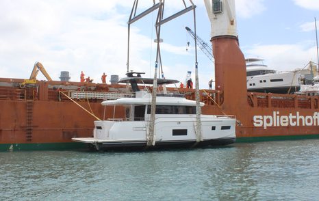 Sirena 58 attached to a crane after being lifted down to the sea from an orange ship.