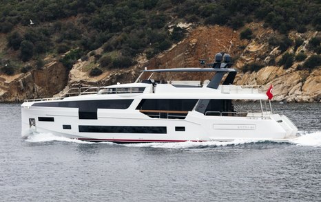 Side view of Sirena 88 underway, heading port direction in front of cliffs and vegetation.