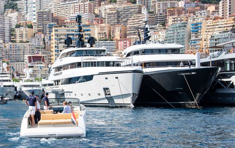 Superyachts berthed in Port Hercule with a tender in the foreground and views of Monte Carlo aft