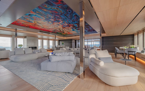 Side angle view of main salon onboard superyacht WANDERLUST. Cream chaise longue in foreground with additional cream coloured sofas and seats in background. 