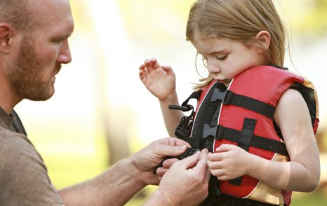 Little girl getting help putting on a lifejacket 