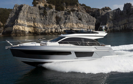 Azimut 53 Fly underway, surrounded by sea with cliffs in background.