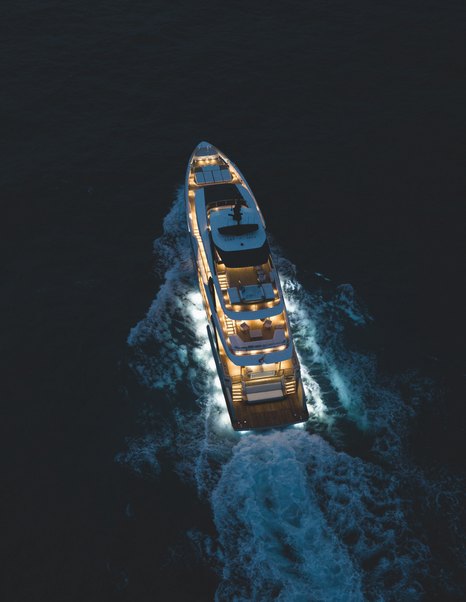Custom Line Navetta 38 underway at night showing illuminated decks and full exterior layout from above