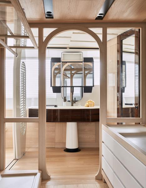 Portrait image of Owner's bathroom on board Sanlorenzo 44 Alloy superyacht. Framed windows border image looking forward to sink and dark wood fixtures.