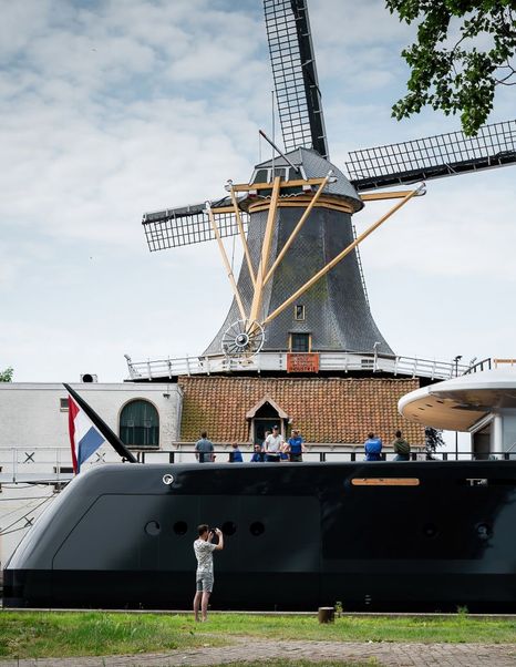 Shot of Feadship Superyacht Thalassa (Project 826) stern with workers on and windmill in background