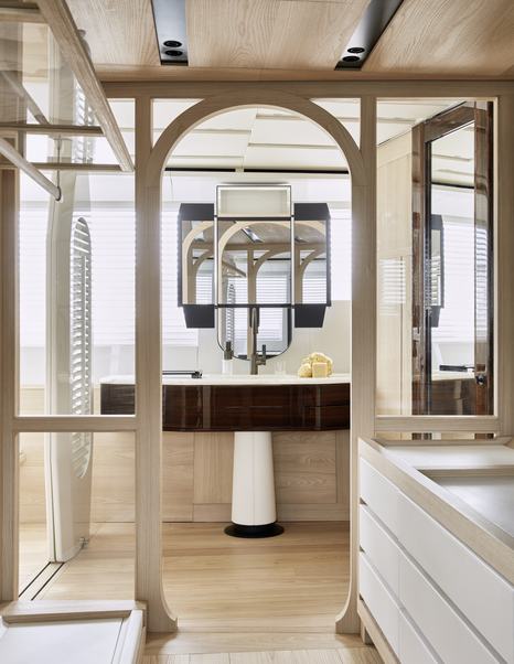 Portrait image of Owner's bathroom on board Sanlorenzo 44 Alloy superyacht. Framed windows border image looking forward to sink and dark wood fixtures.