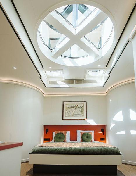 Owner's cabin on motor yacht Scintilla Maris with high ceilings, orange furnishings and contemporary art