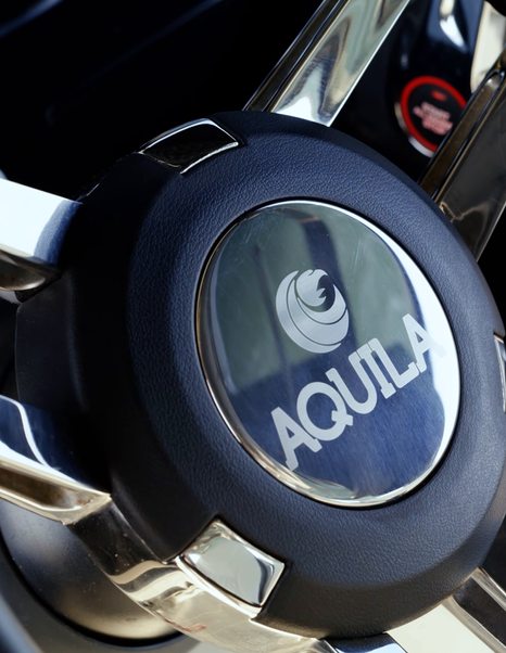 Aquila 45 Sport helm steering wheel with Aquila branding, showing modern powercat driving position detail