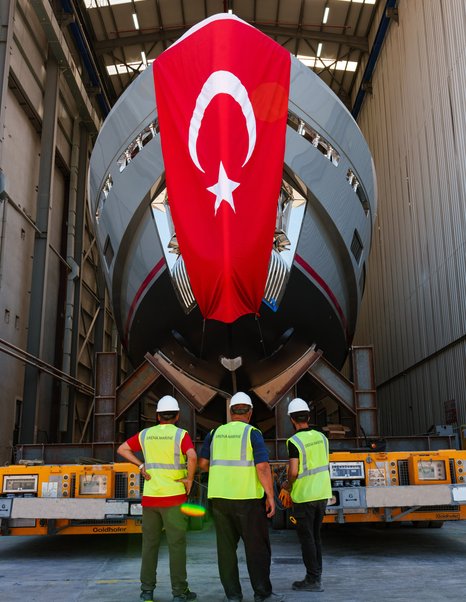 Workers underneath bow of First Sirena 118 superyacht with flag