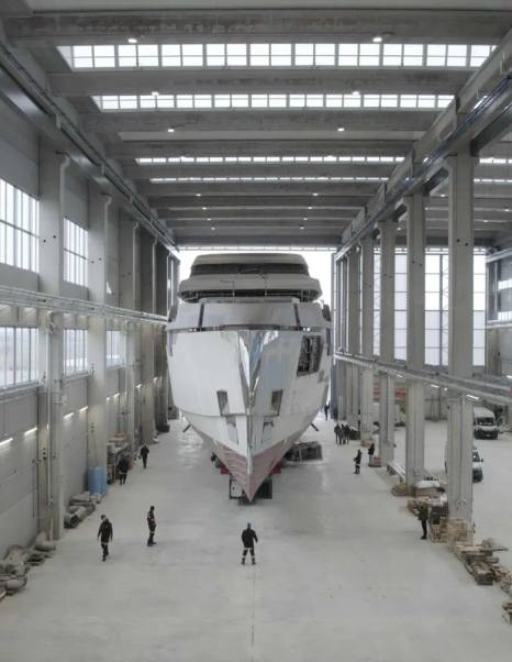 Flagship Amer 74 Steel superyacht bow in shipyard with workers beneath