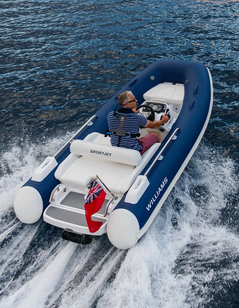 Man on small RIB tender on clear water