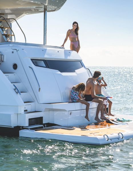 Sunseeker Manhattan 68 for sale at Fort Lauderdale International Boat Show, image shows family on bathing platform with deck slightly lowered into the water