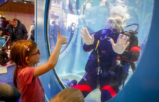 Girl waving at man scuba diving