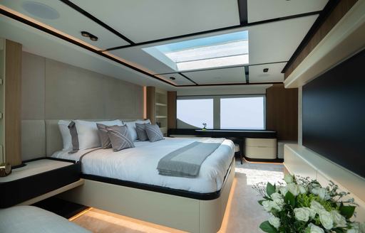 Master cabin onboard the Majesty 111. Central berth facing starboard with wide window in background.