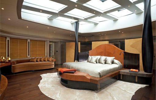 Master cabin onboard superyacht AV, central berth with sofa in background and huge sunroof directly above bed.