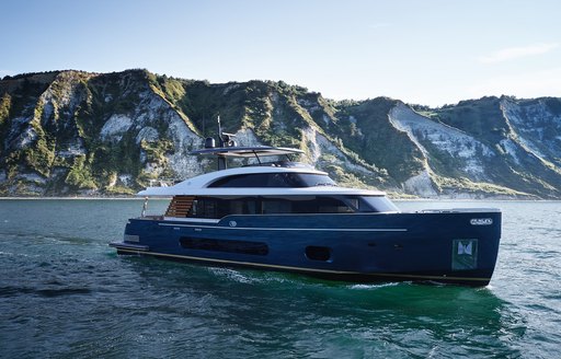 Magellano 25 Metri at anchor, surrounded by sea with cliff face in background