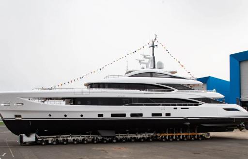 Benetti yacht CALEX a 50m B.Now yacht shown on trailer at launch, flags atop the yacht from bow over radar mast and to stern, grey day, port side profile shown