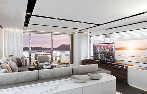 comfortable grey sofa faces flat-screen TV in the white main salon of Astondoa AS8 yacht as sun sets outside