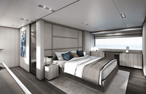 Owner's cabin onboard Ferretti 1000, central berth with wide window on far side and glimpse of en-suite behind berth.