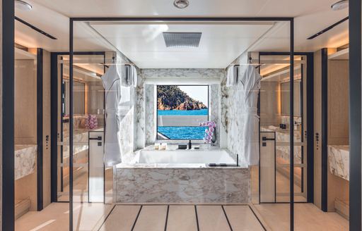 Owner's private bathroom onboard CRN RIO superyacht. Central square bath overlooking large window in background.