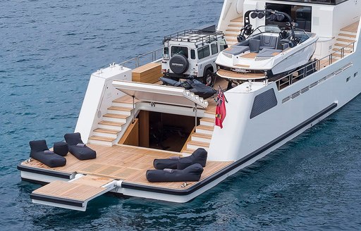 Aft of YXT 24 Evolution, with tender and four by four on main deck, with four sunloungers on swim platform