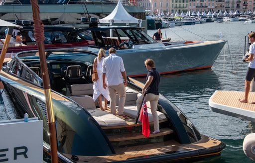 Group of three people standing on a tender among superyachts on display at the Cannes Yachting Festival