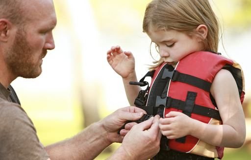 Little girl getting help putting on a lifejacket 