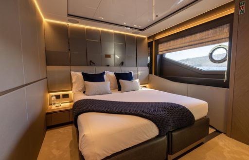 Guest cabin onboard Sunseeker 100 Yacht, central berth with nightstand either side plus oblong window to starboard.