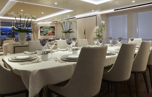 Dining area onboard Heesen 'Project Triton', dining table with eight seats, adjacent to stretch of windows