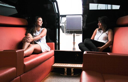 Two women in interior of limousine tender talking on comfortable seating