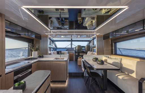 Overview of Pearl 62 main deck interior, galley and dining area in foreground, overlooking lounge area and helm station in background