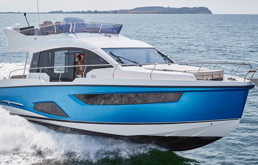 Front view of Sealine F430 underway, with Owner at helm. Surrounded by water.