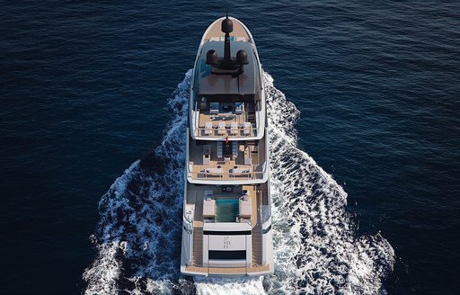 Bird's eye view looking down on Sanlorenzo 57Steel, swimming pool visible aft with multiple sun loungers on sun deck. Surrounded by sea.