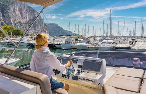 female at helm of motor yacht in marina