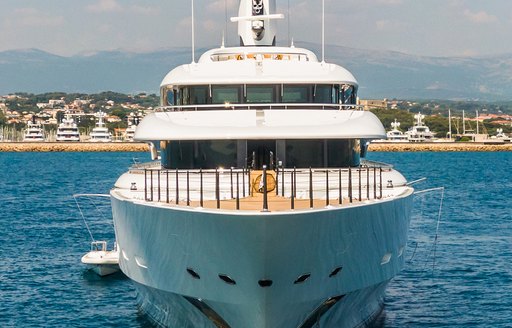 Frontal view of the bow on megayacht IJE, surrounded by sea and superyachts berthed in a marina in the background.