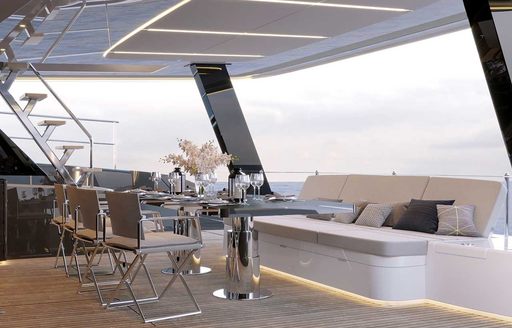 Sunreef Yachts Power ECO 60 exterior salon looking over towards starboard quarter deck, steps in background leading up, dining table and banquette seating