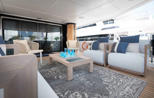 Exterior seating situated on aft main deck of Majesty 111. Large armchairs with blue cushions surround a coffee table.