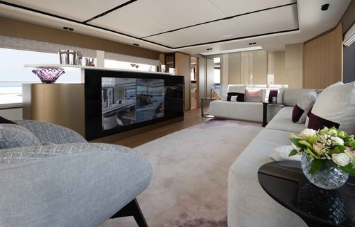 Plush lounge area onboard the Majesty 111, large flatscreen TV surrounded by white upholstered sofas and armchairs.