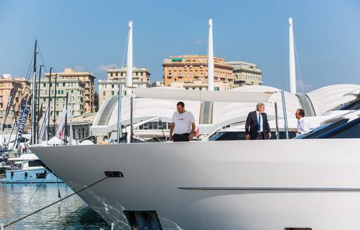 Dealer stands on bow of boat with client during Genoa Boat Show