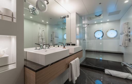 Ensuite facility in master cabin onboard superyacht WANDERLUST. His and hers sinks in foreground with wet room in background 