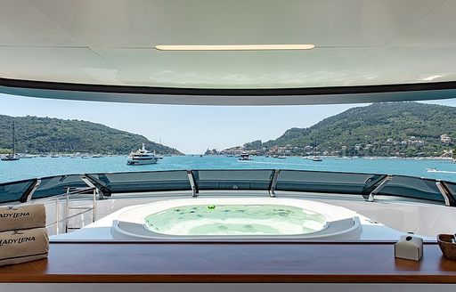 Spacious Jacuzzi onboard Sanlorenzo Lady Lena, overlooking panoramic views of elevated terrain and anchored yachts