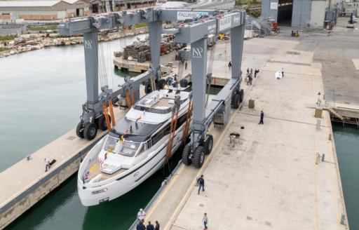 Overview of Extra X99 Fast being launched in dock, being lowered by a crane on to the water.