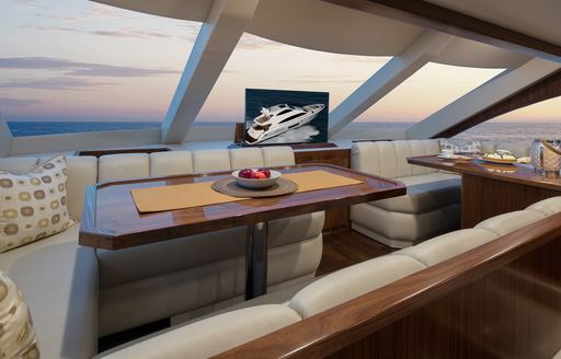 Lounge area/dinette on bridge deck of Viking 75 MY. Table surrounded by abundant windows and diner style wraparound seating.