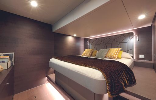 The owner's cabin features a central bed, mood lighting and warm brown and cream tones