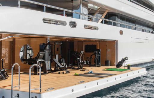 Side view of gym onboard megayacht IJE, fold down waterside terrace fitted out with golf equipment.