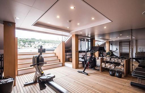 Gym onboard YXT 24 Evolution, exercise equipment in centre and round edges of room, open doorway with steps leading to swim platform