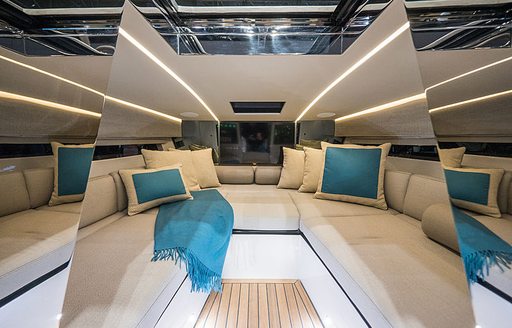 Inside of Nerea Yachts NY24 , U shaped seating with teal cushions and blanket